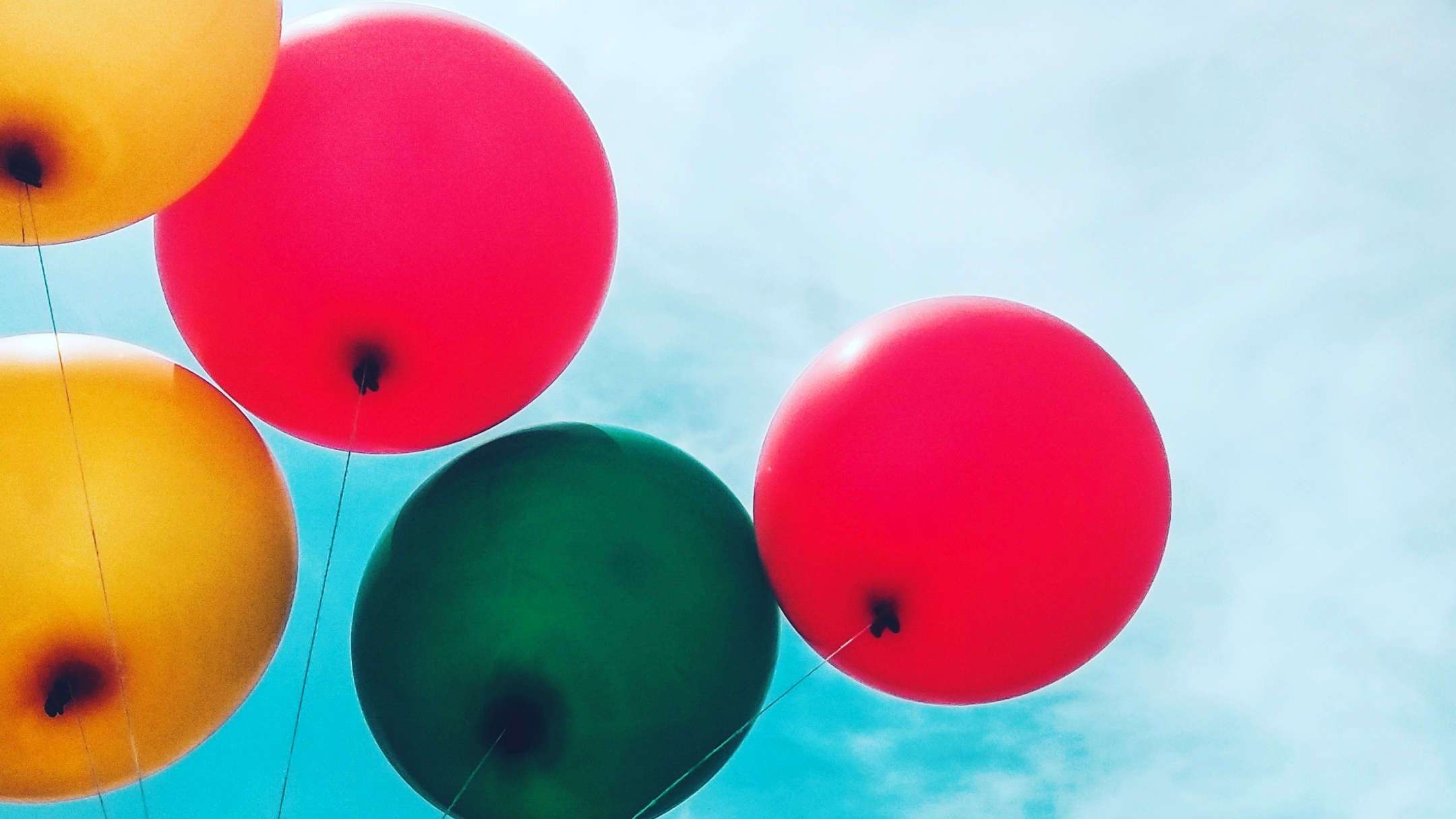 Ballons in verschiedenen Farben mit einem blauen Himmel im Hintergrund.